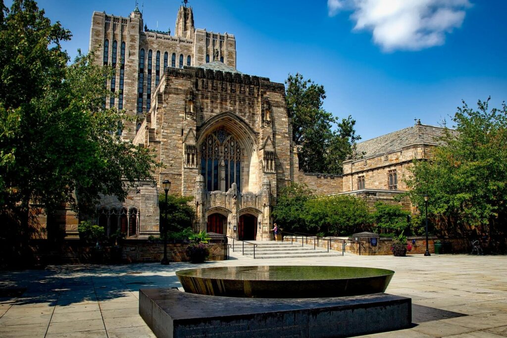 Entrance of the Sterling Memorial Library at Yale University, featuring gothic architecture and lush surroundings.